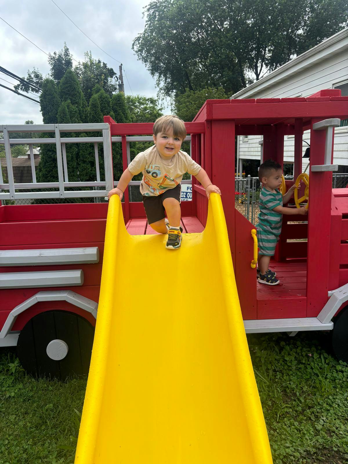 Child on a yellow slide, another child in a red play structure