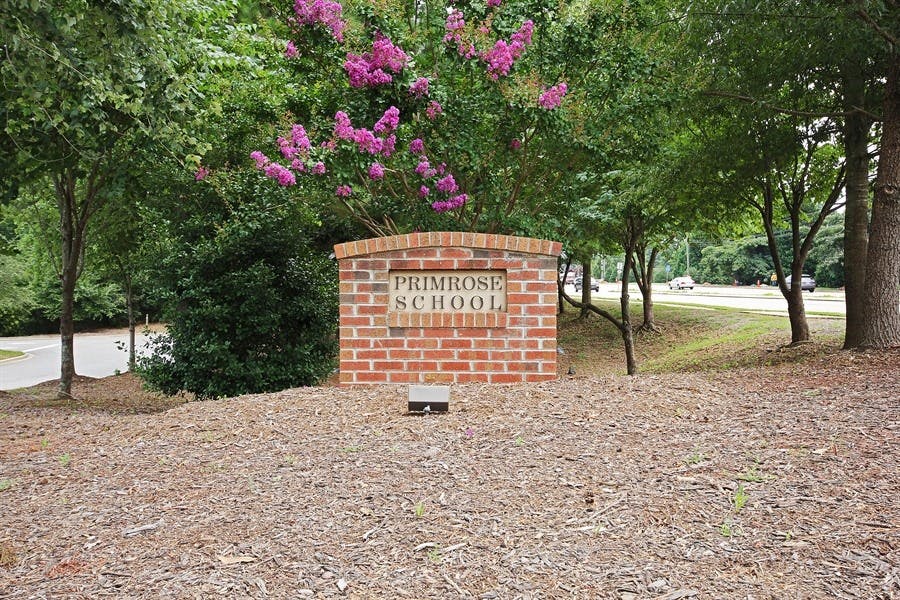Brick sign for Primrose School surrounded by trees