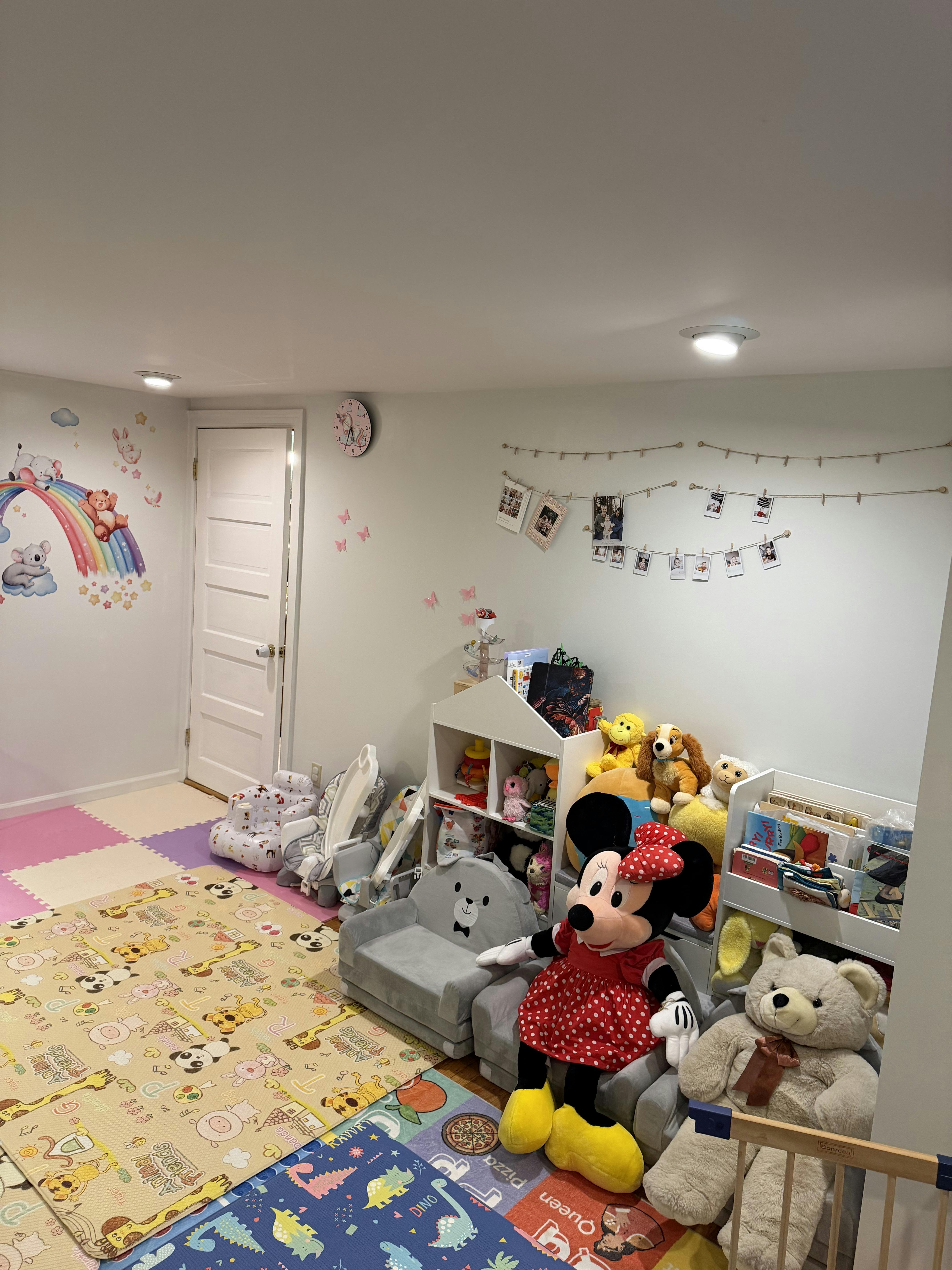 A playroom with colorful playmats, shelves of toys, and stuffed animals