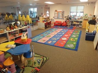 Preschool classroom with colorful rug and small tables