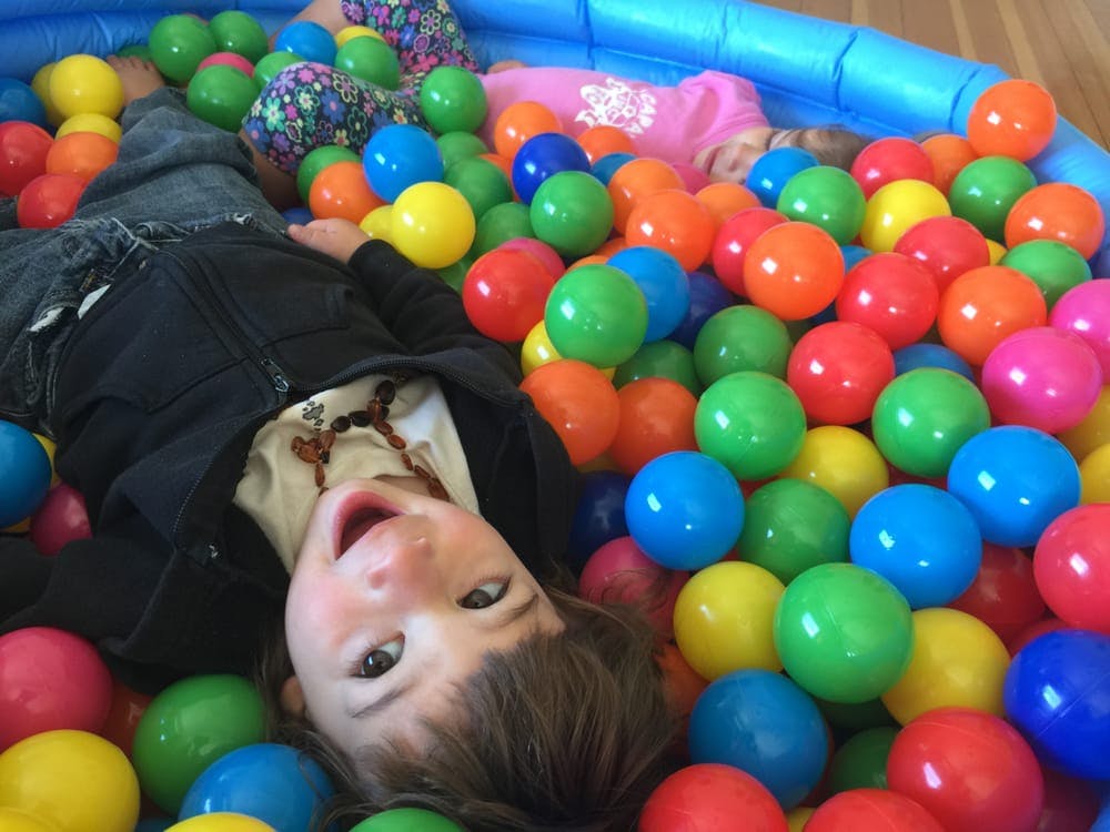 Child lying in a ball pit with colorful plastic balls