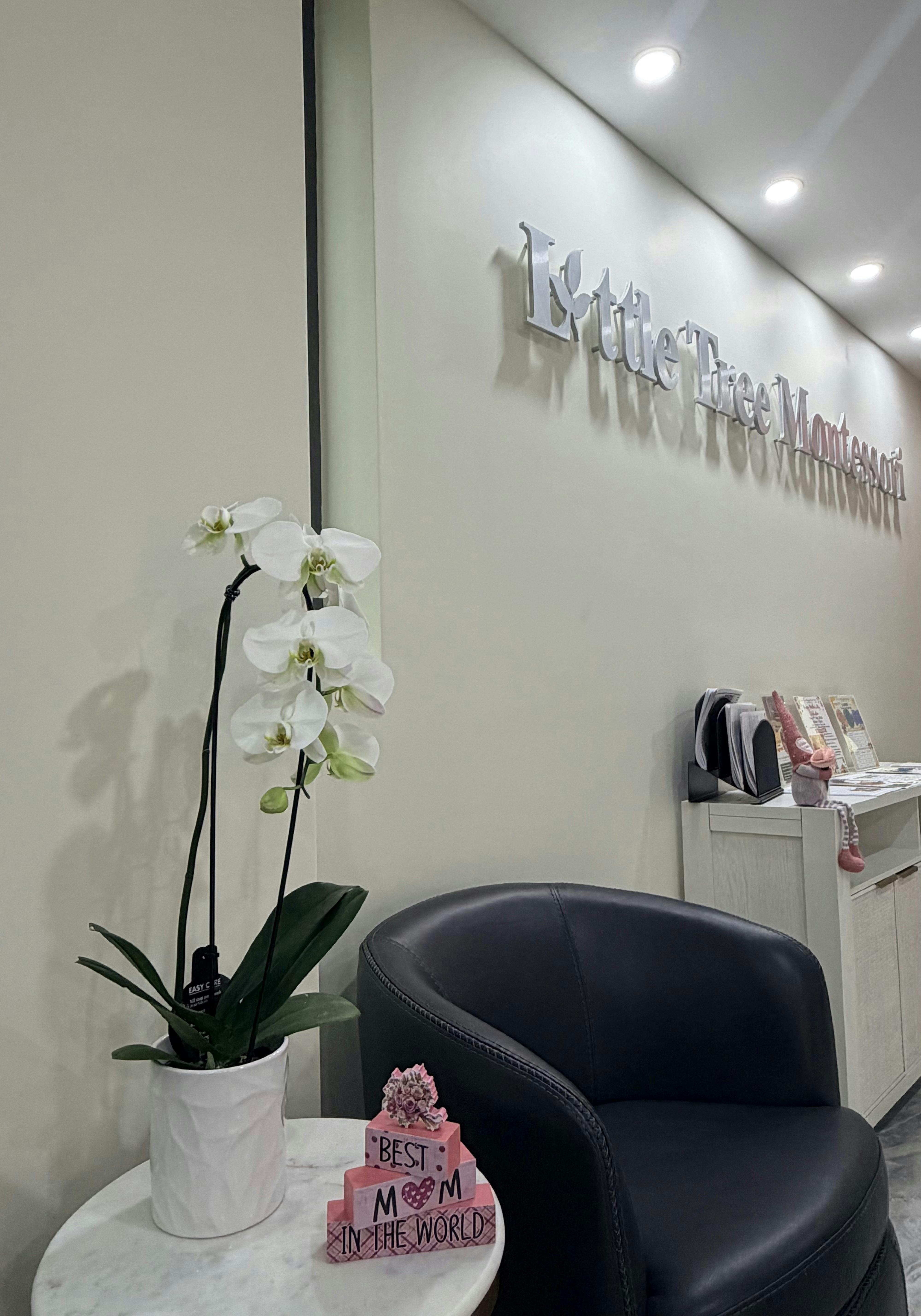 white orchid plant on a table next to a black chair and a sign on the wall