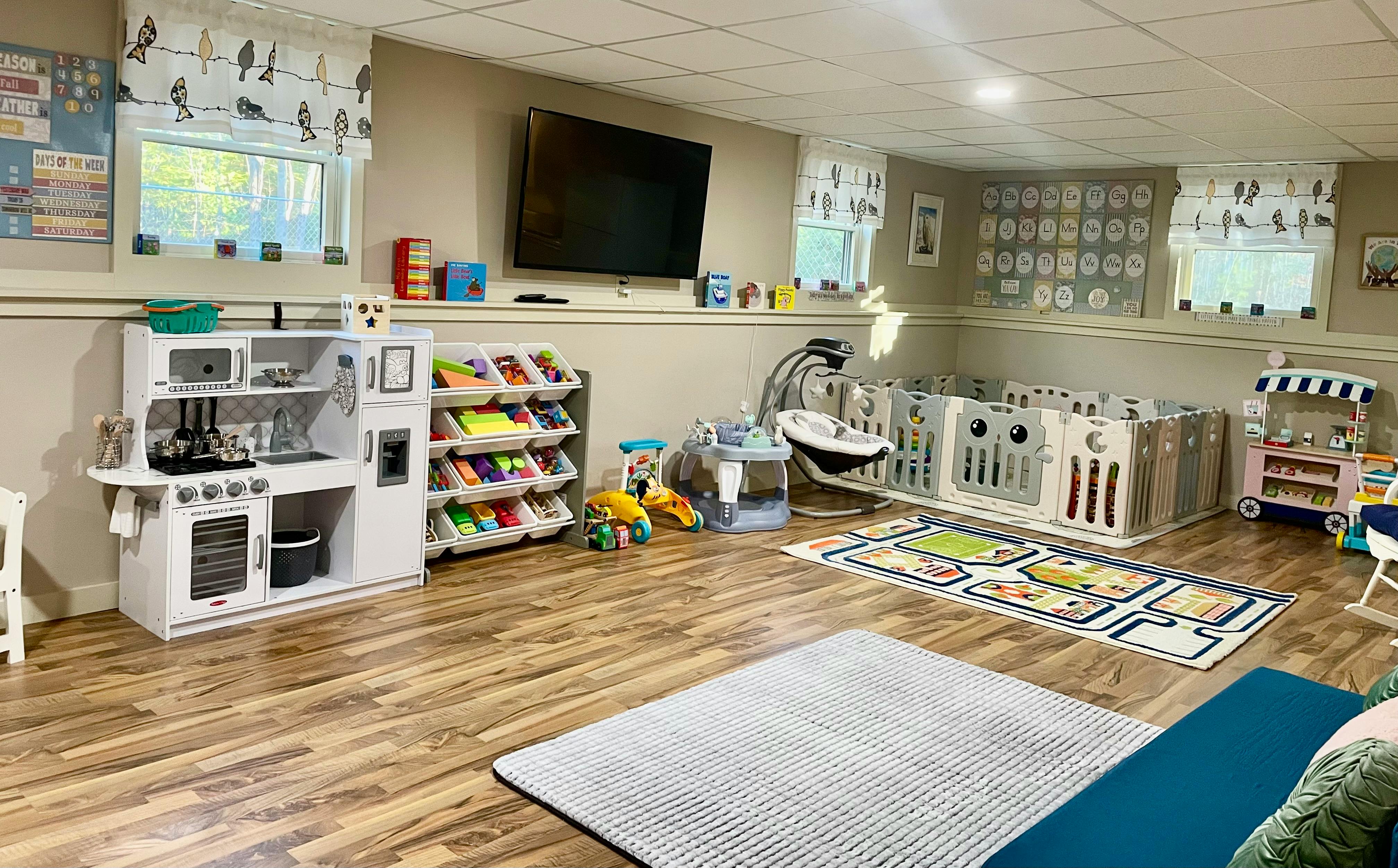 Playroom with toy kitchen, book shelf, playpen, and rugs