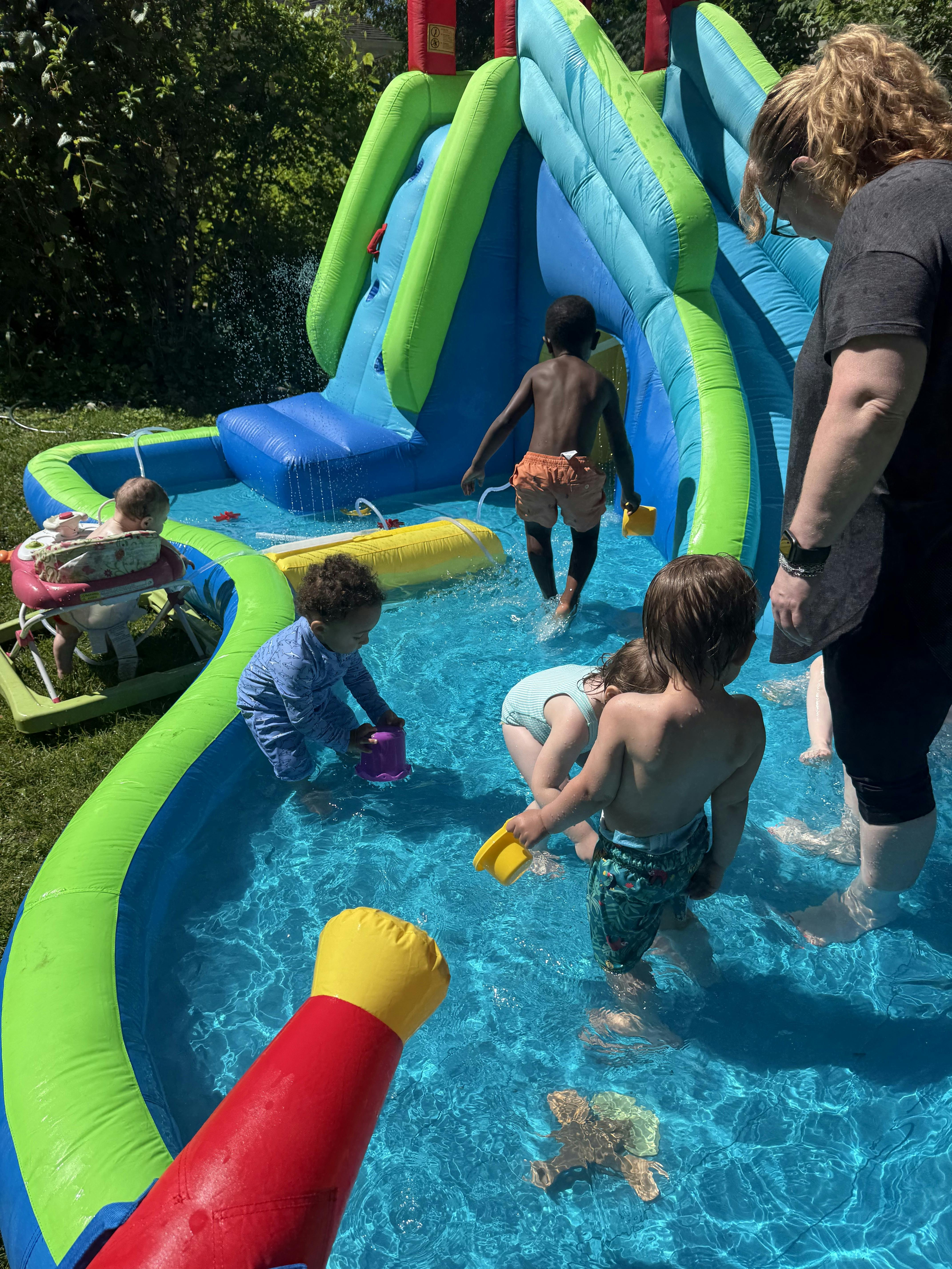 Children playing in an inflatable water slide pool