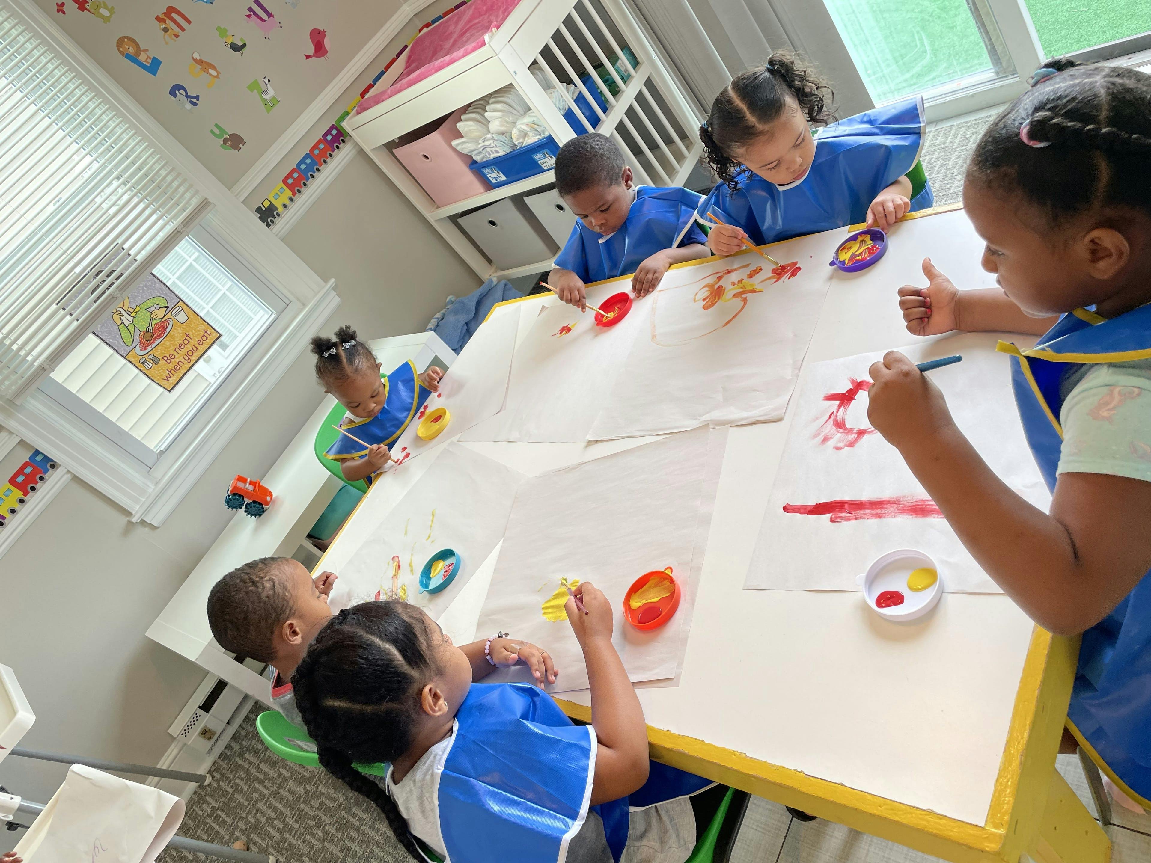 Children painting at a table in a classroom