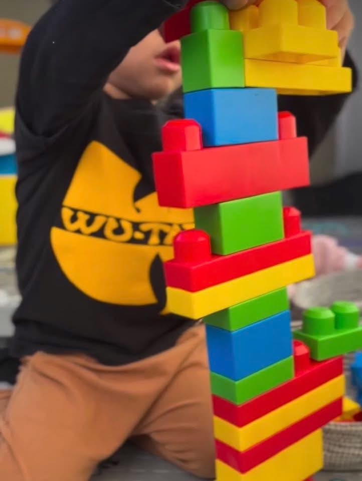 Child building a tall tower with colorful interlocking blocks