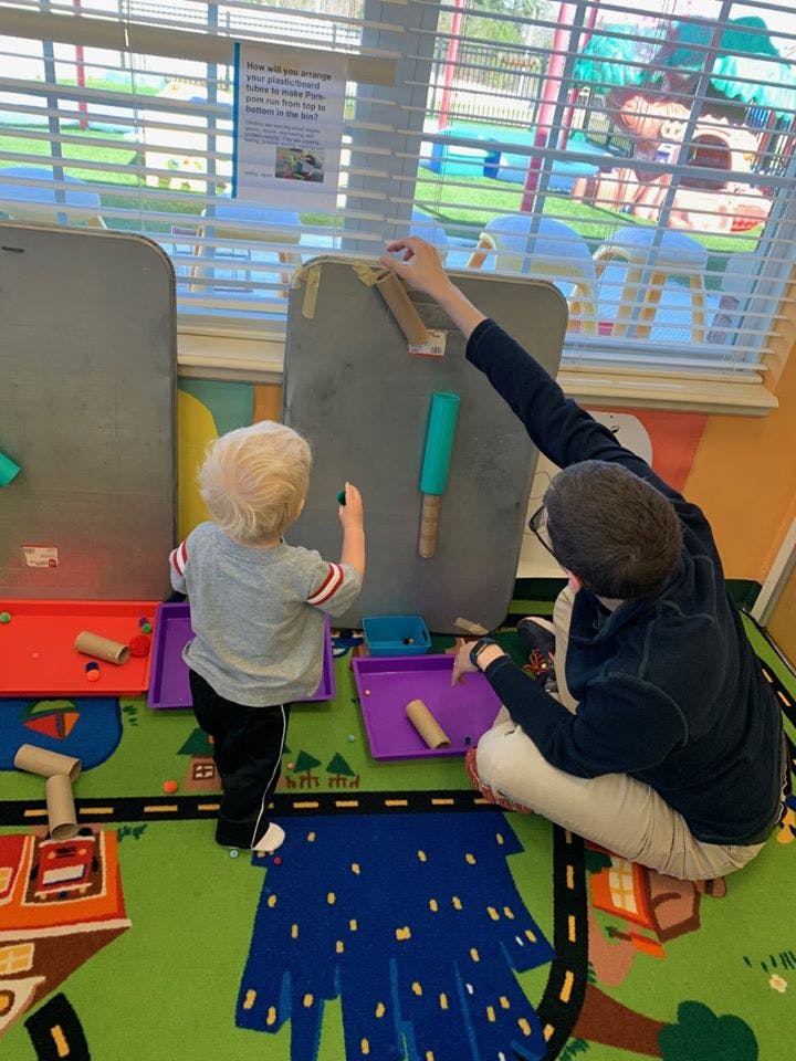 Adult and child playing with objects on a board