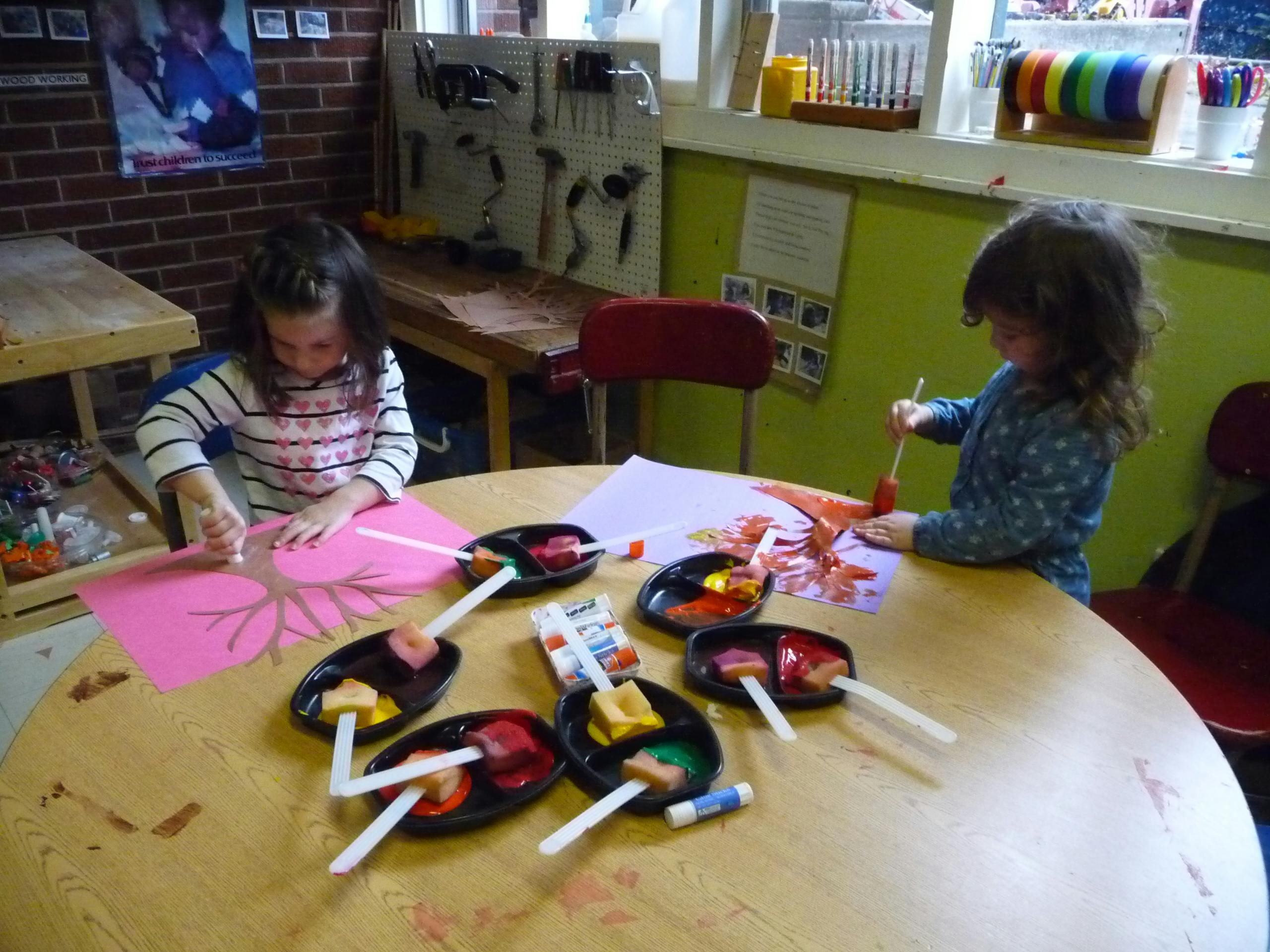 Two children painting at a table in a classroom