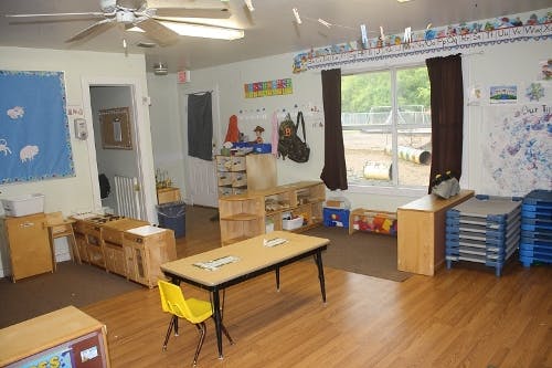 Classroom with tables, chairs, and a window looking out to a playground