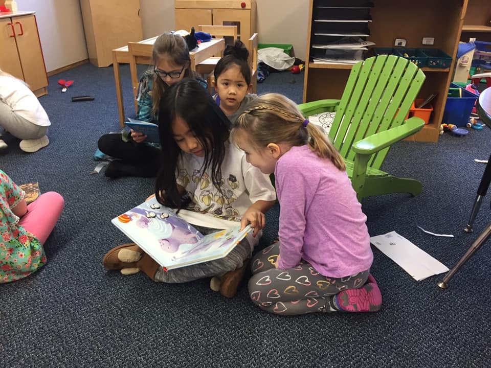Children sitting on the floor looking at a book
