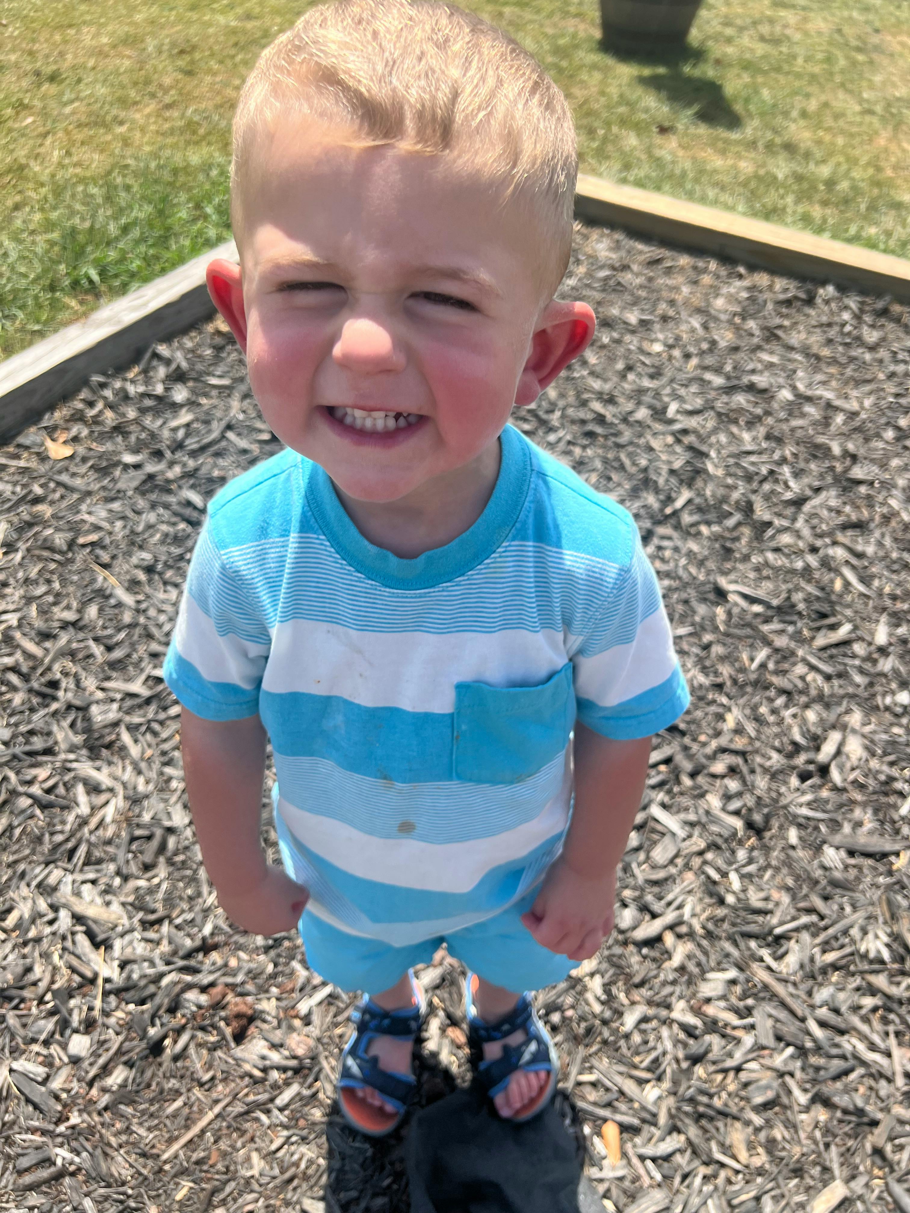 Child in a striped shirt standing on wood chips