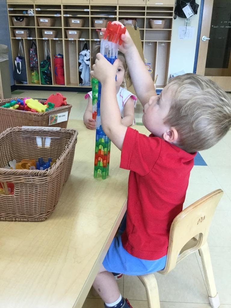 Child playing with a tall colorful building toy at a table