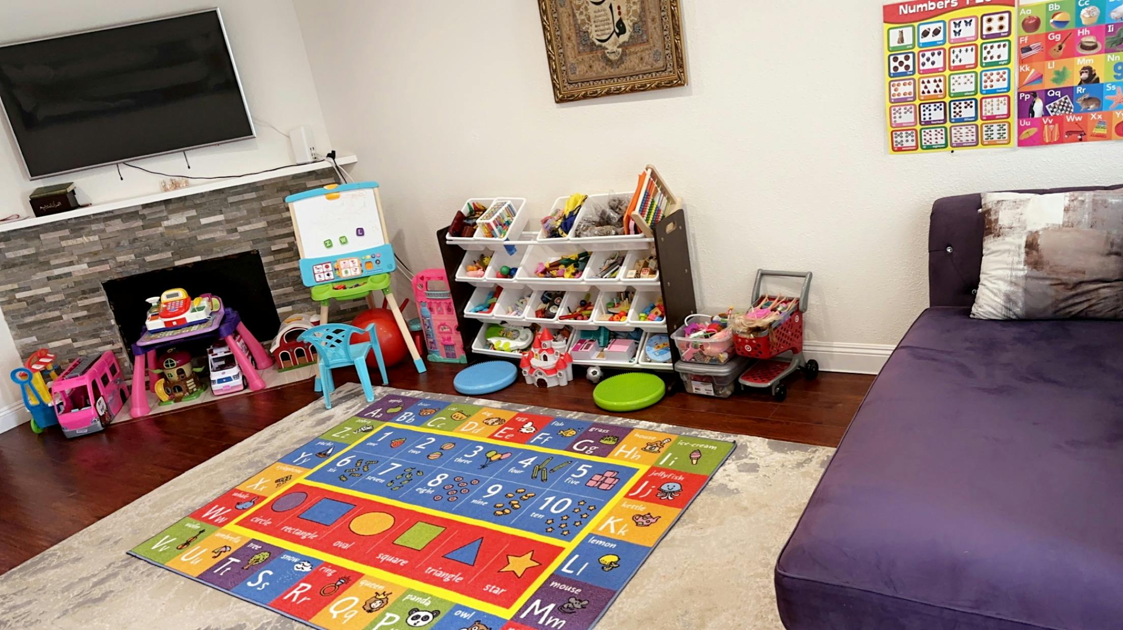 Playroom with a colorful alphabet rug, toy storage, and children's furniture