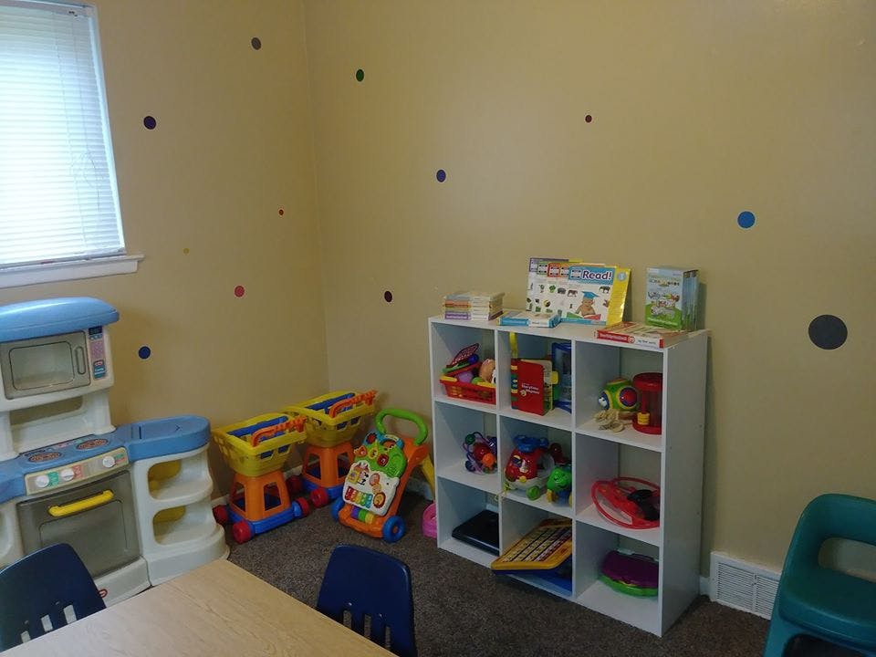 Playroom with toy kitchen, toy shelf, and small table with chairs