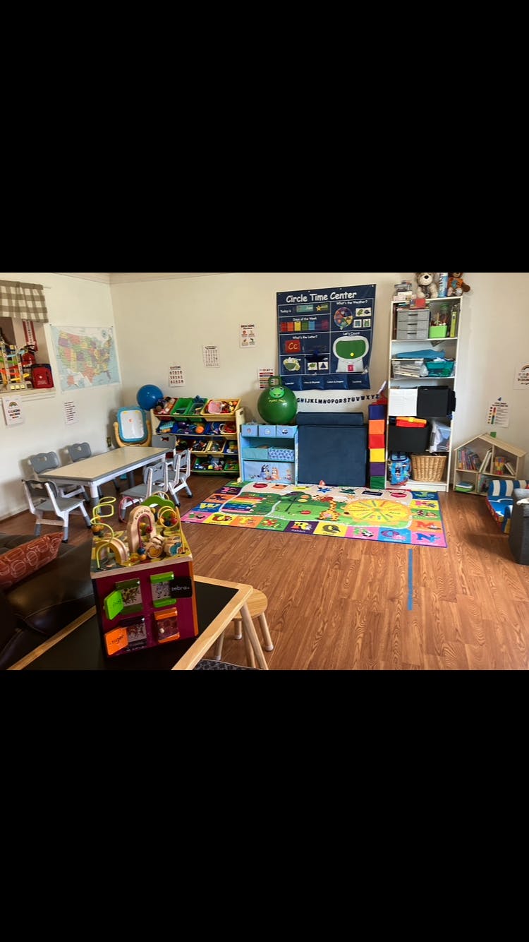 A colorful playroom or classroom with a small table and chairs, toys, and educational posters