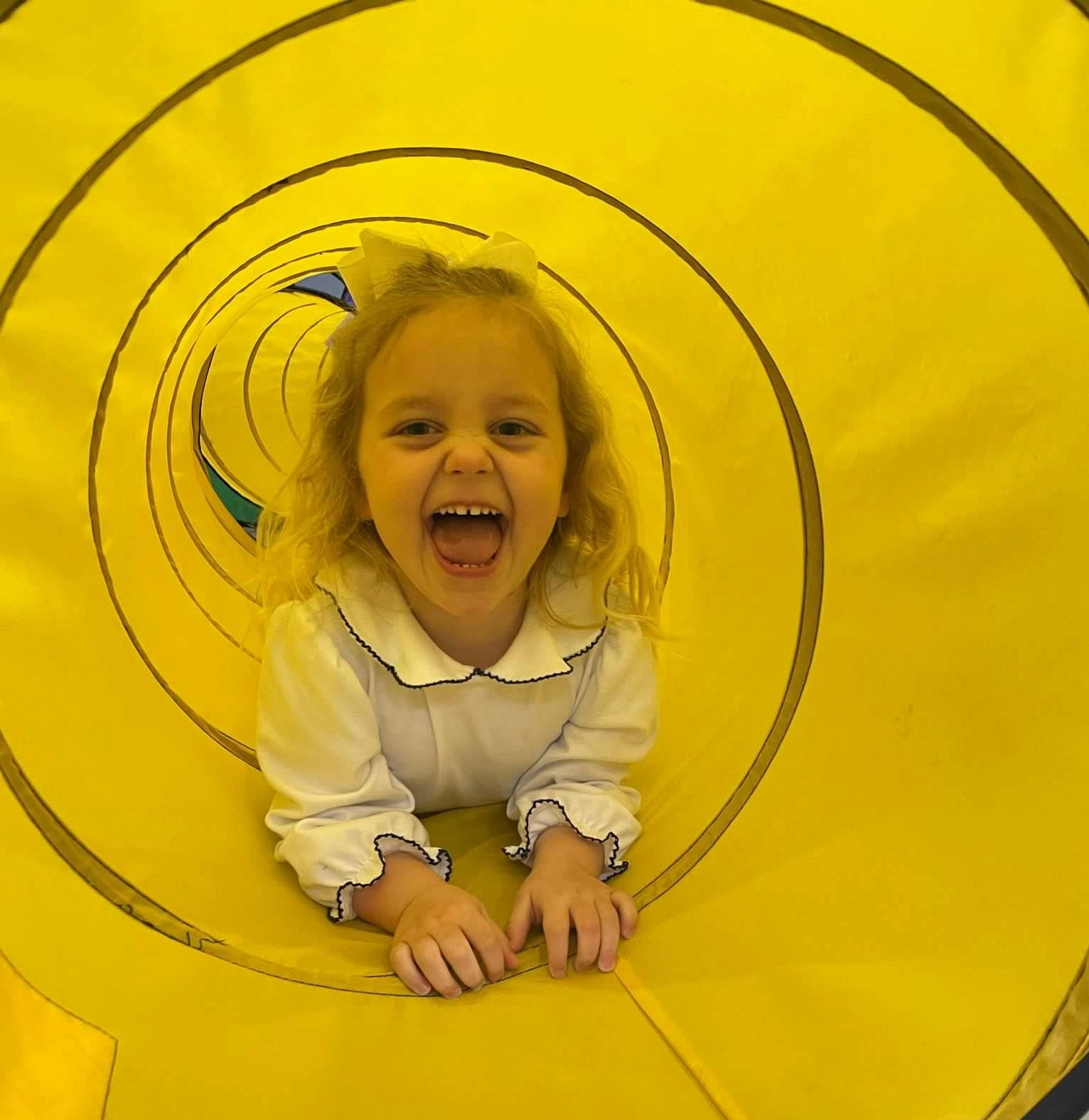 Child in a yellow play tunnel