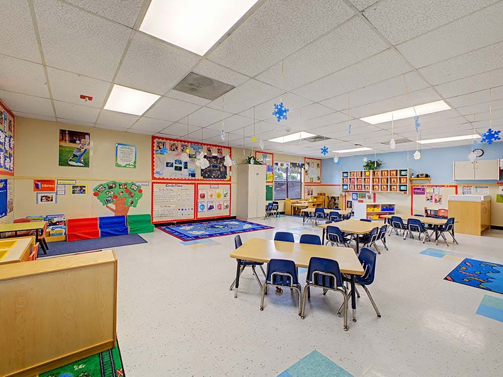 Empty classroom with small tables and chairs, decorated walls and ceiling
