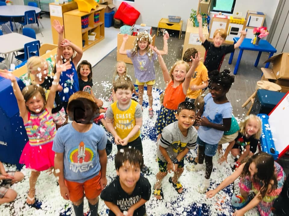 Group of children playing in a classroom with white foam