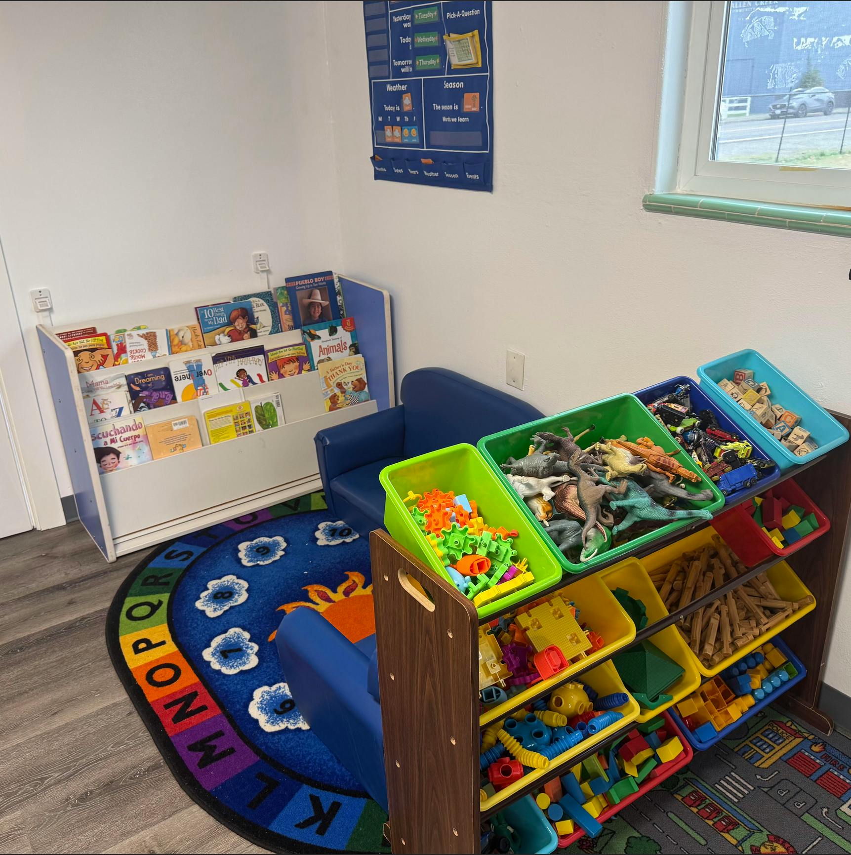 Classroom corner with book display, small couches, and toy organizer bins