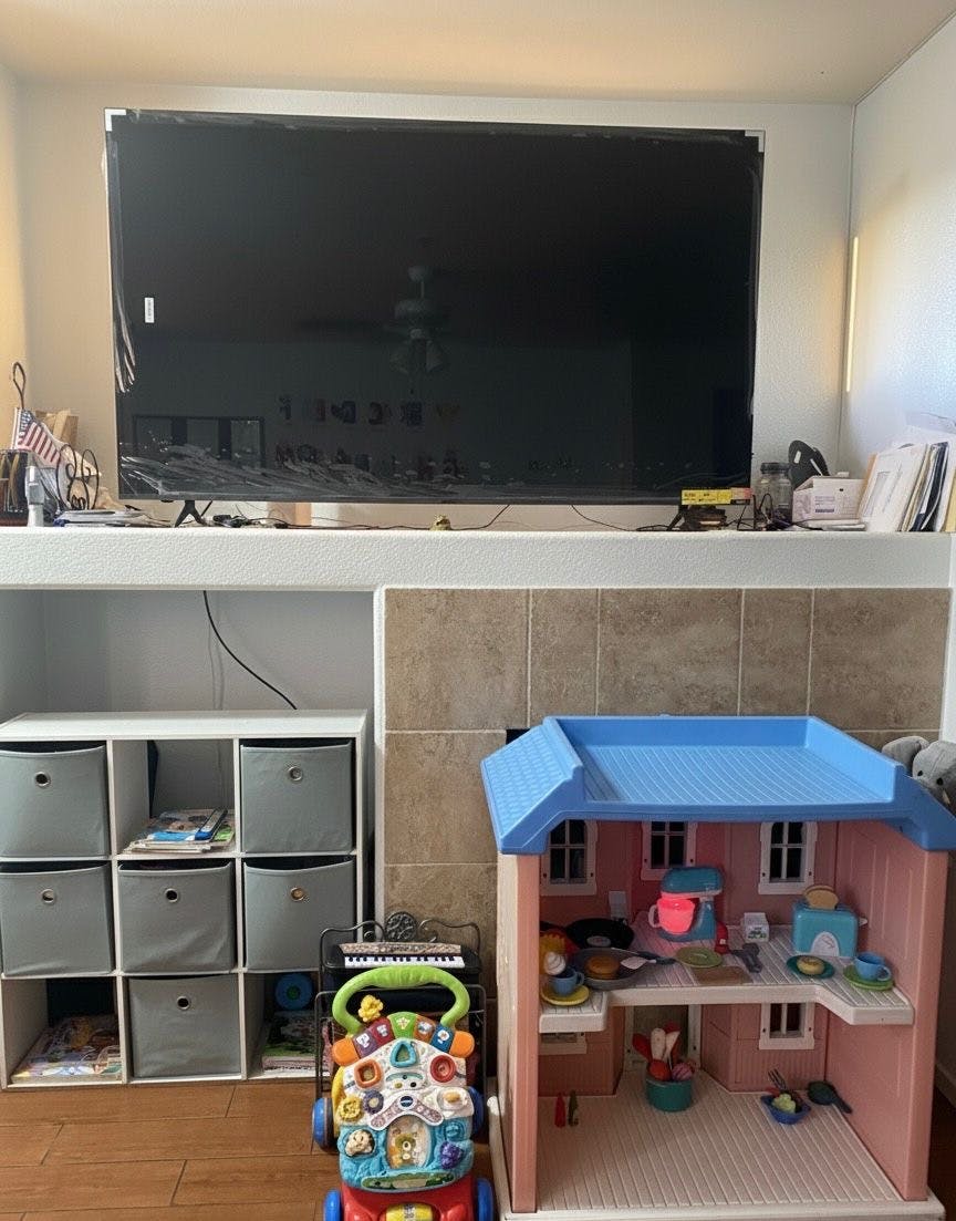 Television above a storage unit, baby walker, and dollhouse