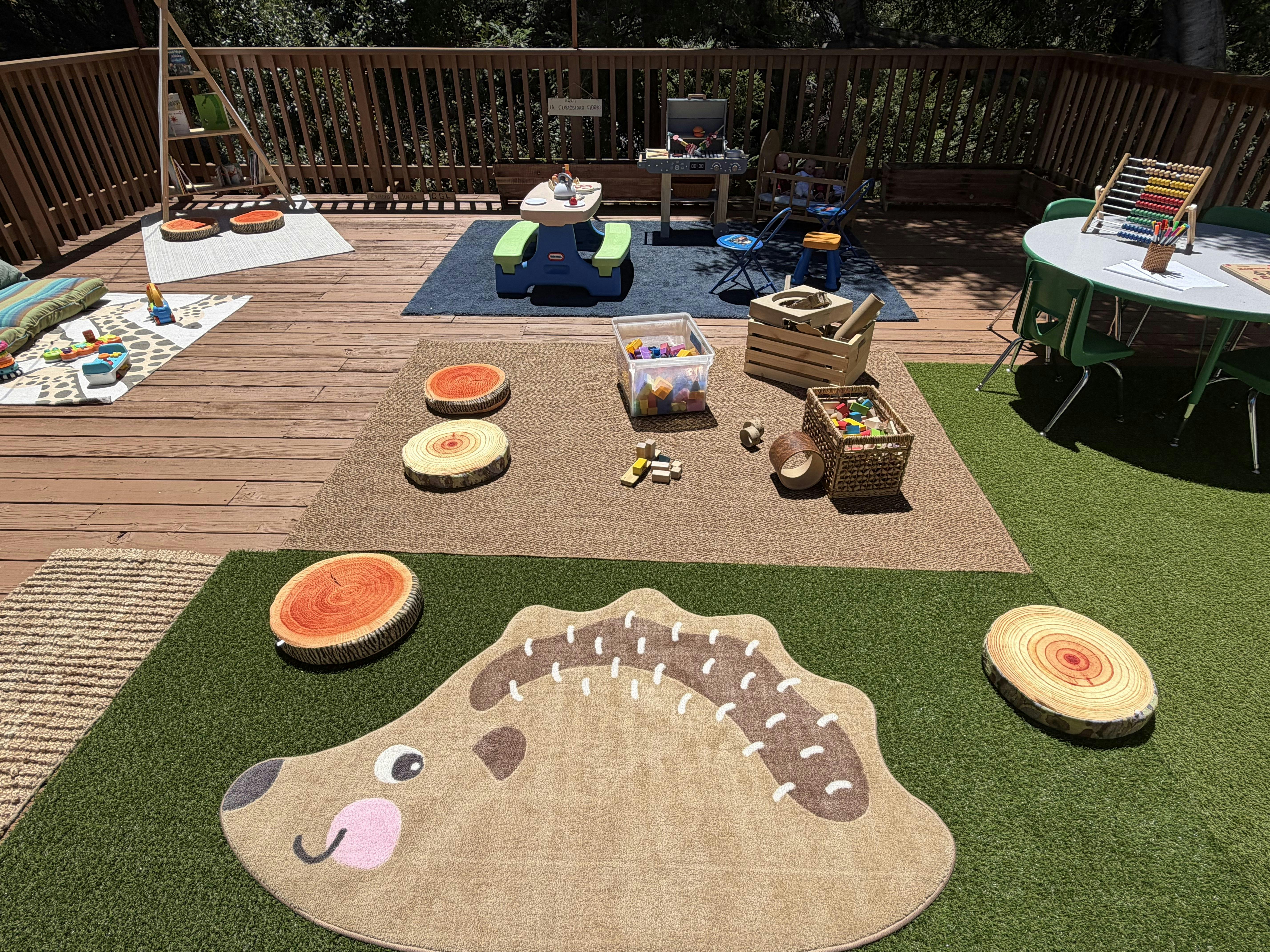 Outdoor play area for children with toys on rugs and artificial grass