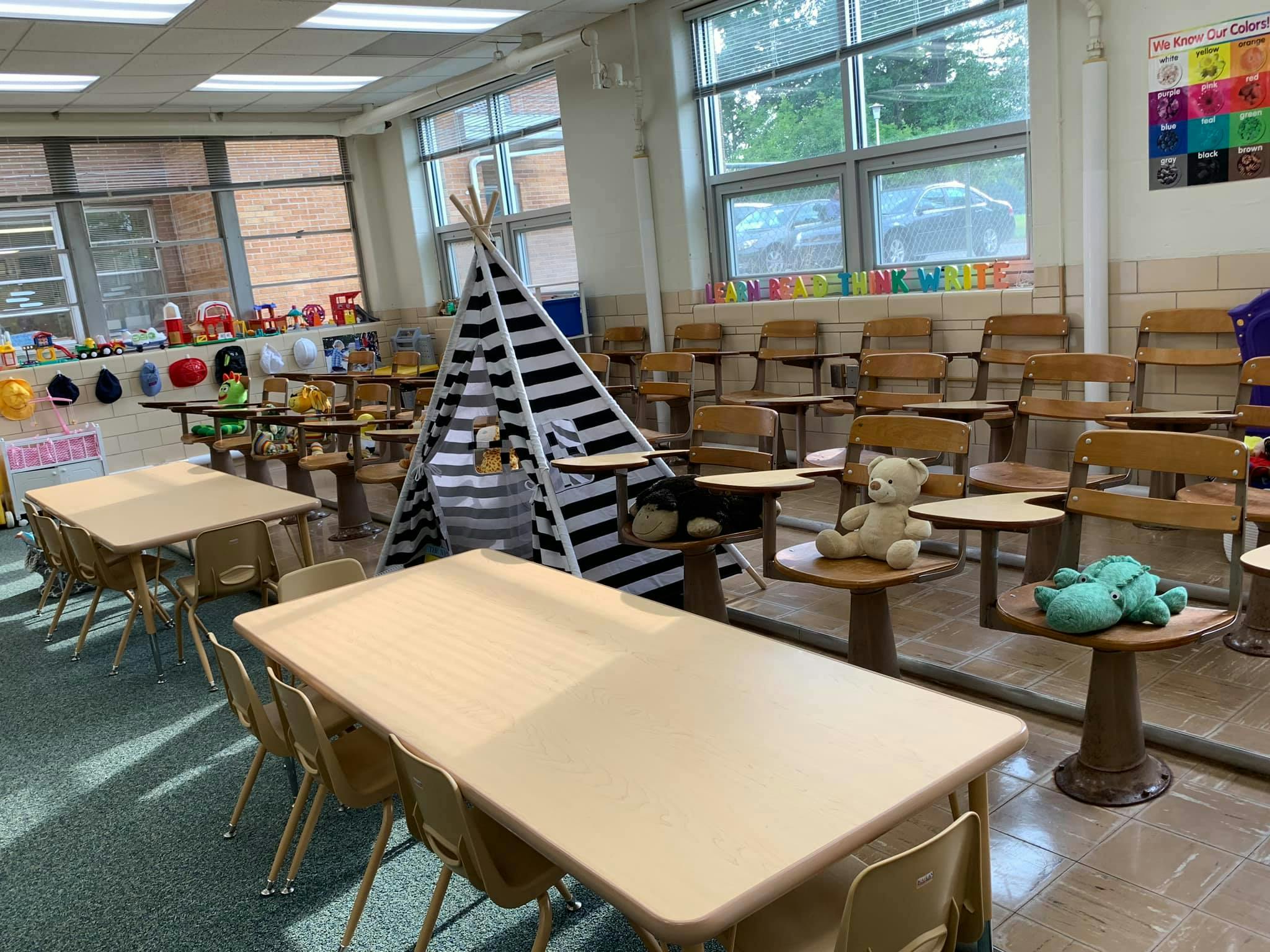 Classroom with small tables, chairs, and a striped play tent