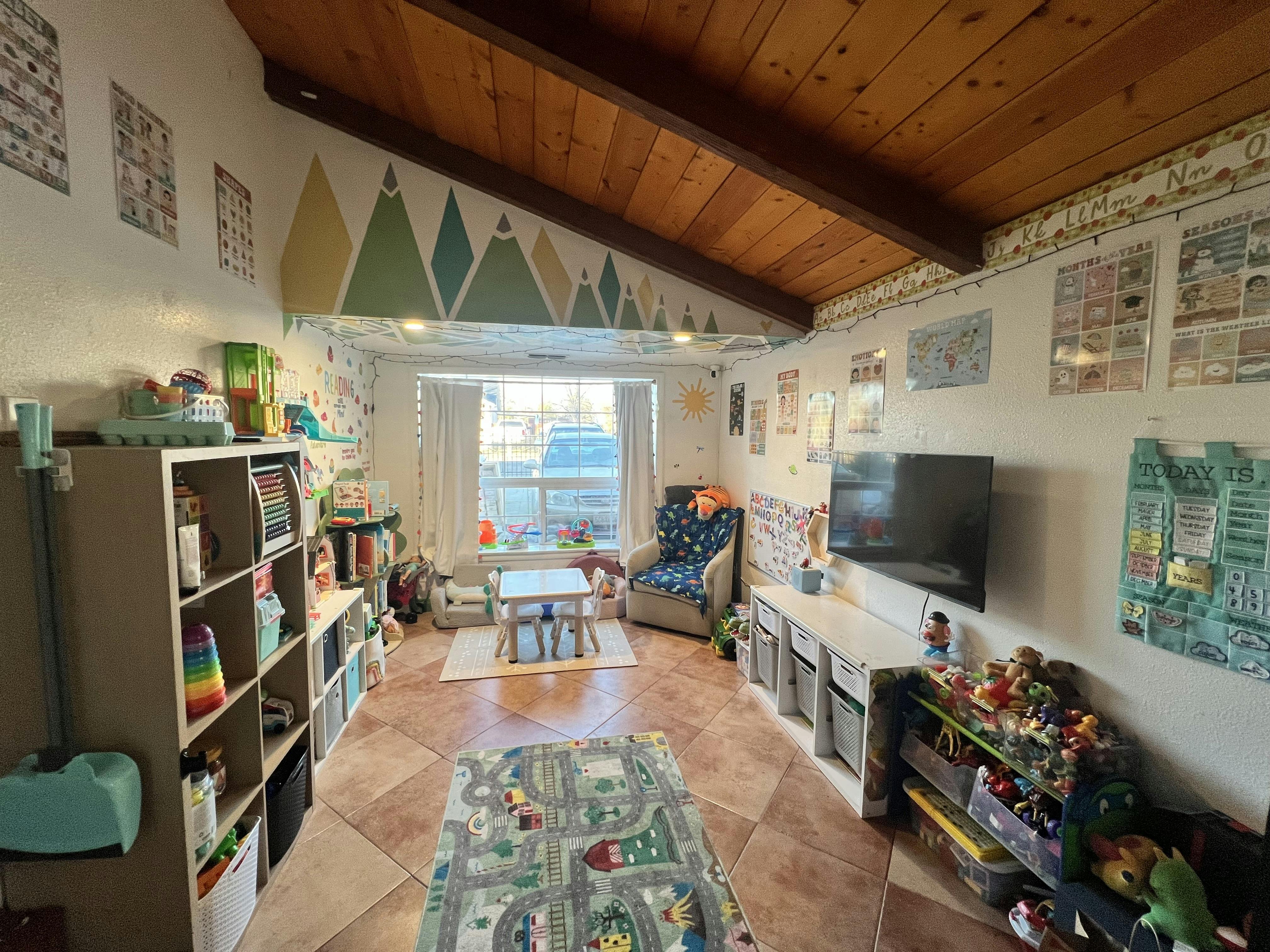 Classroom filled with toys, books, teaching materials, and a small table and chairs