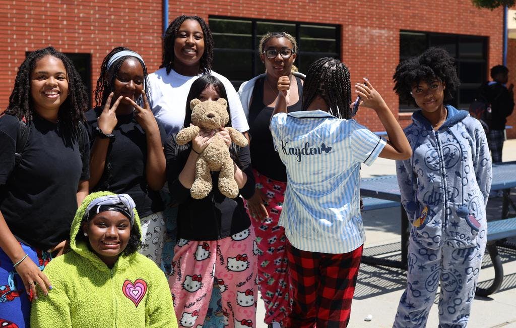 Group of teens in pajamas, one holding a teddy bear