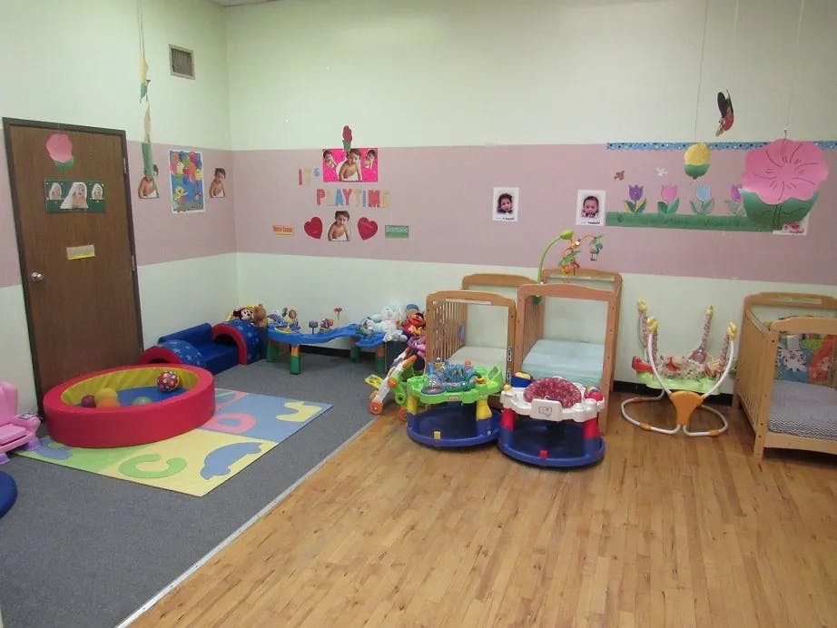 Daycare room with cribs, playmats, and toys
