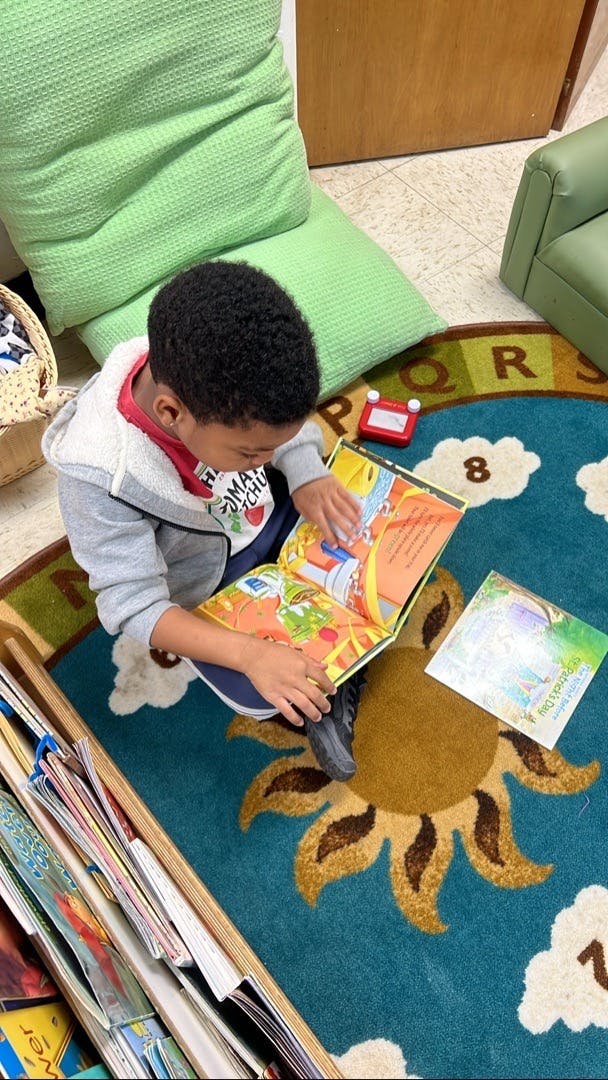Child sitting on a rug and reading a picture book