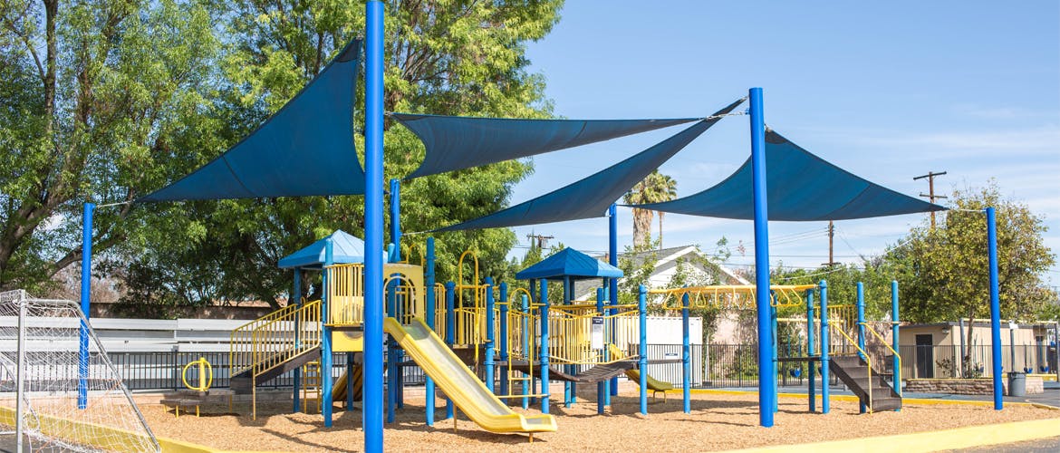 Playground with yellow slides and blue shade canopies