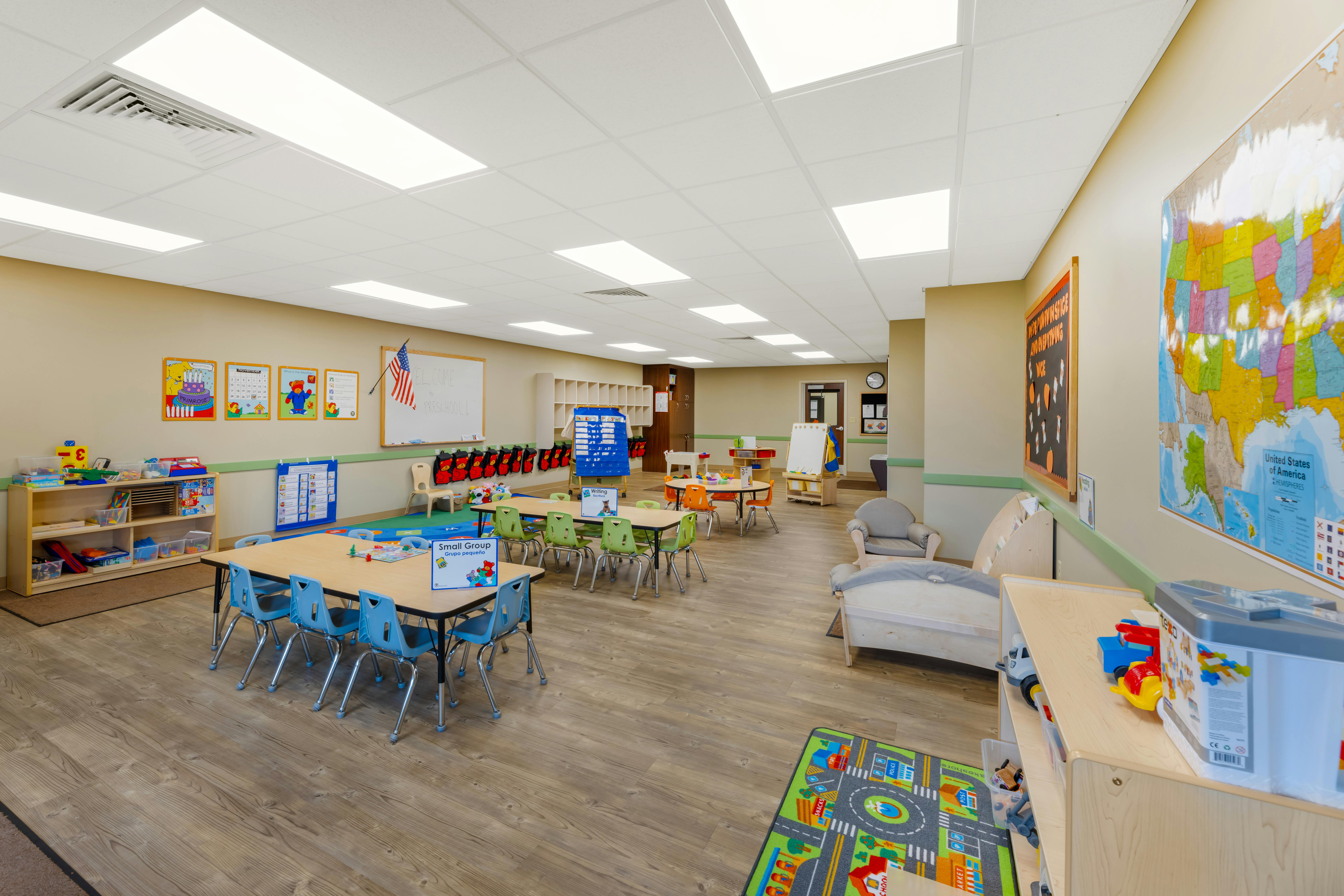 Classroom with small tables and chairs, toys, and educational posters on the walls