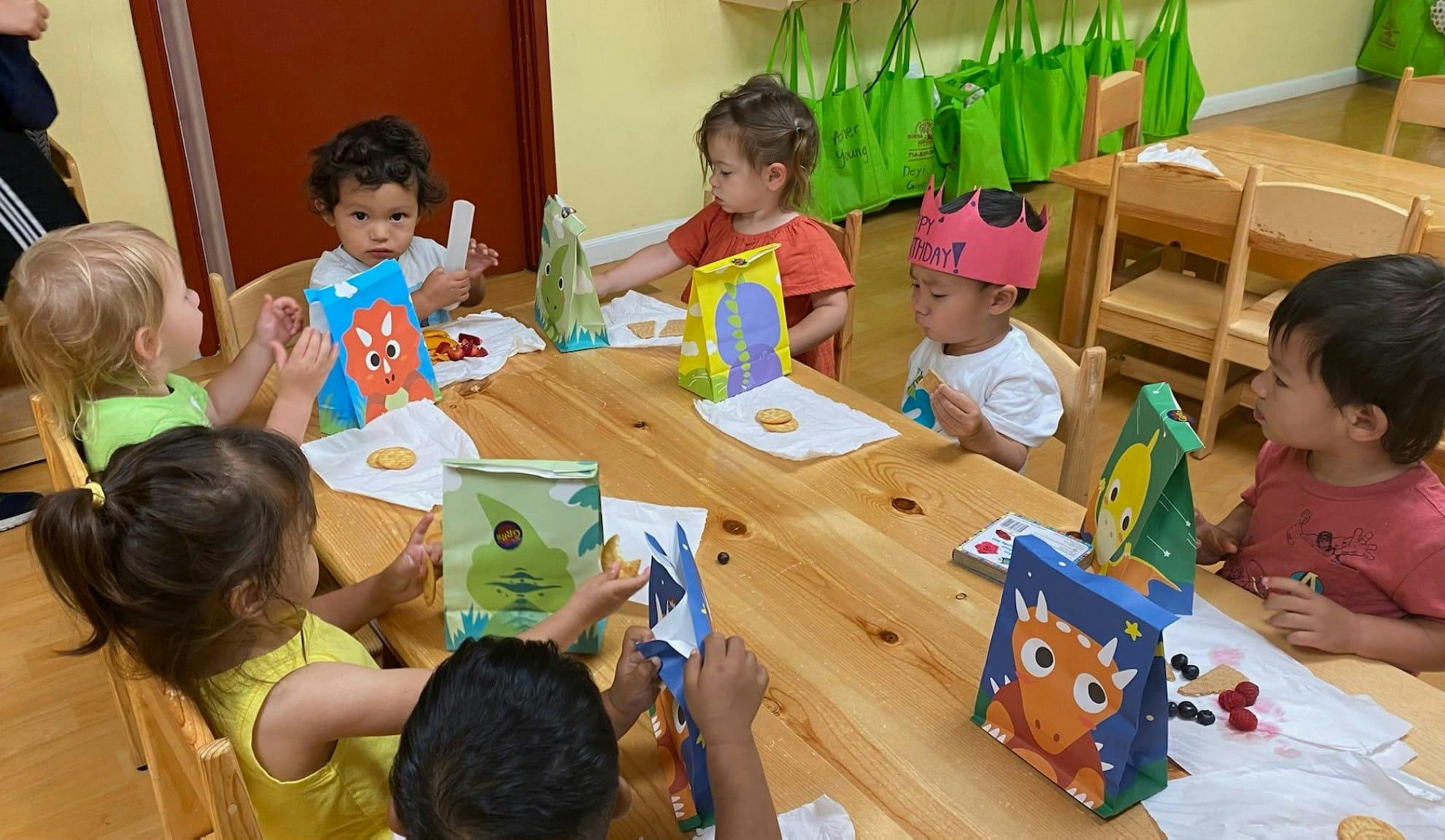 Children sitting at a table with colorful bags and decorated bags