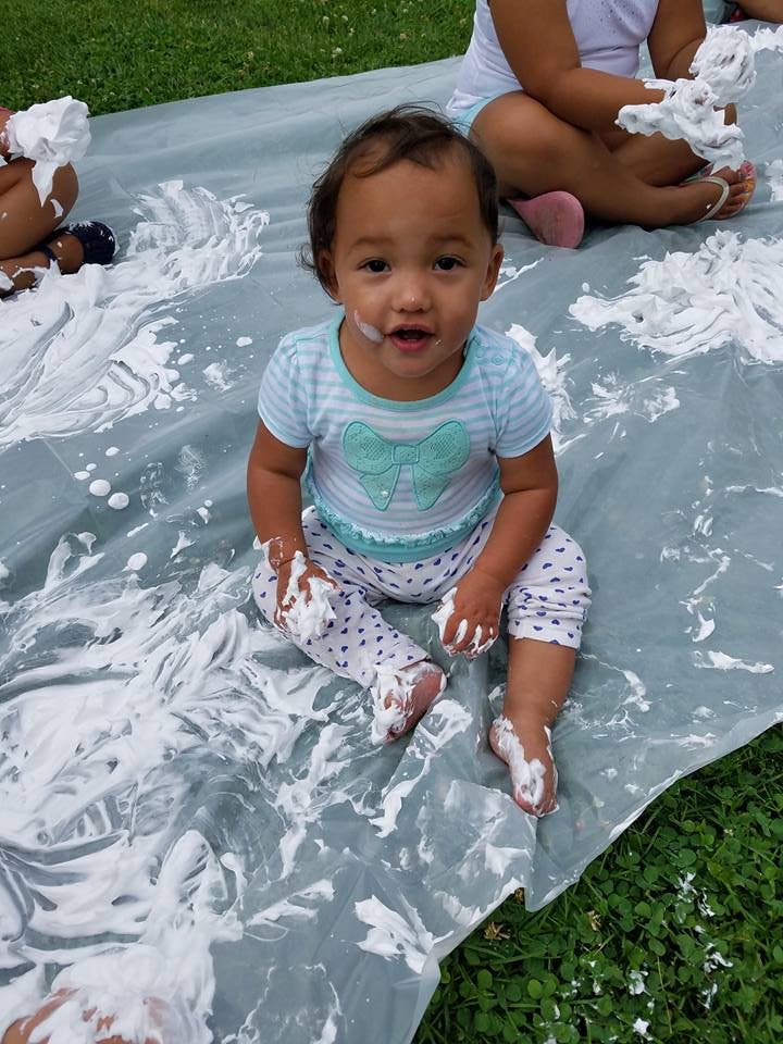 Child sitting on a tarp covered in white foam