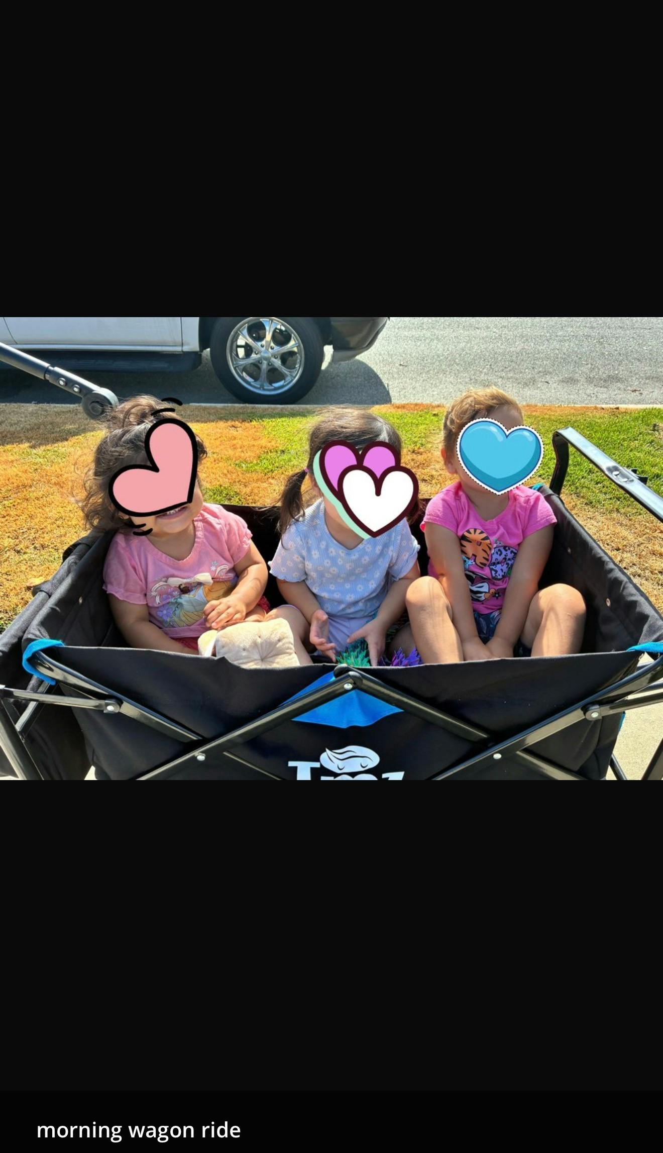 Three children sitting inside a utility wagon