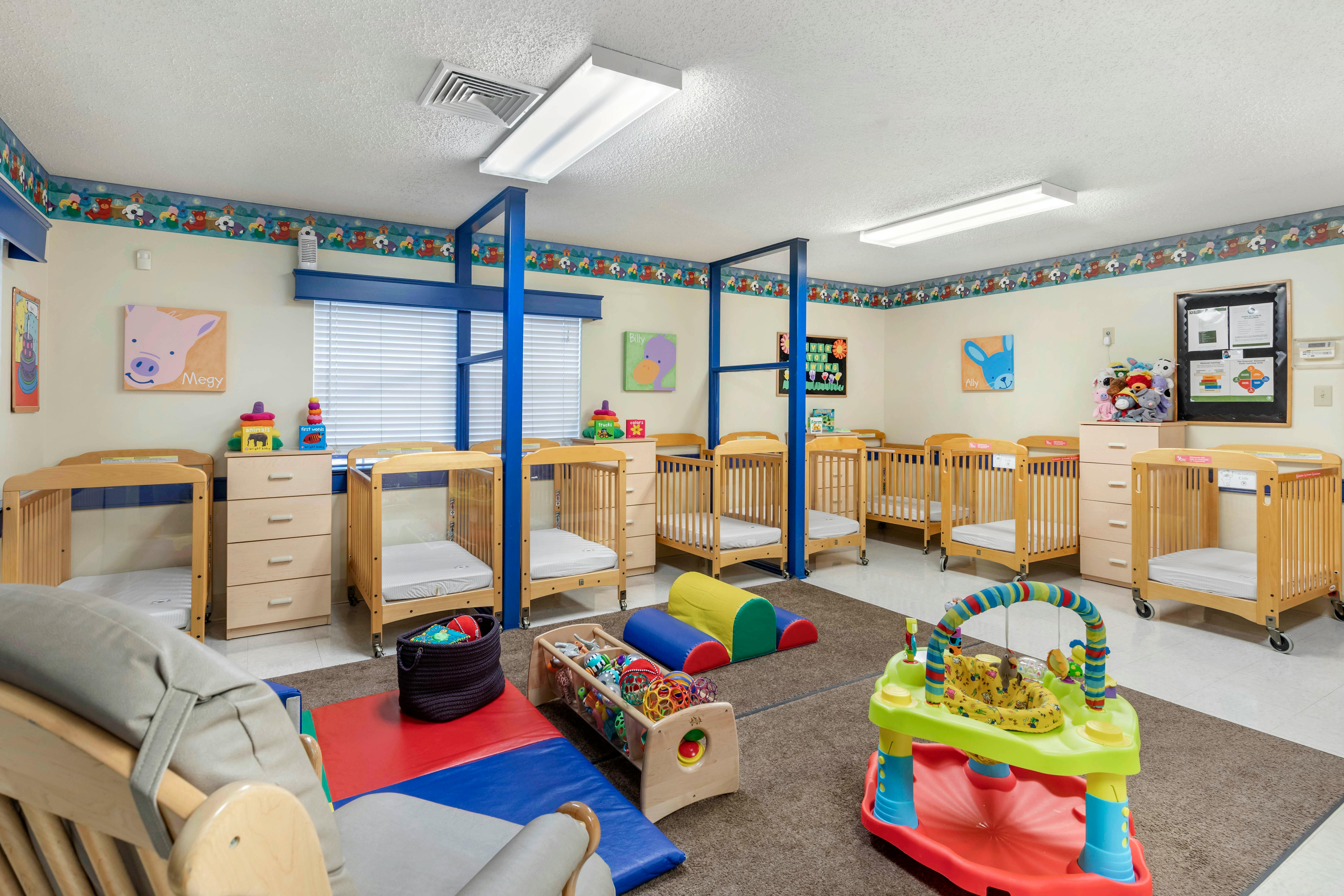 A colorful room with many cribs and baby play equipment