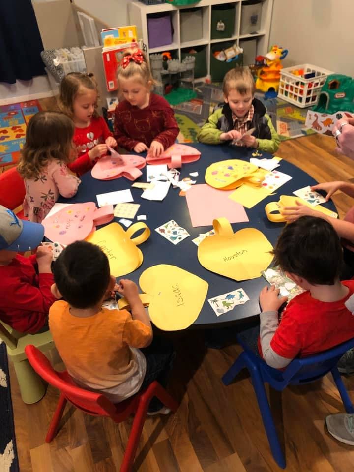 Children sitting around a table doing crafts with paper crafts