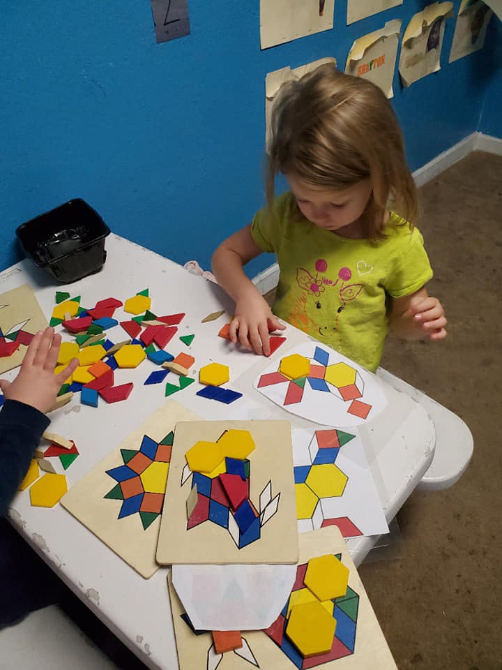 Child playing with colorful geometric shape puzzles at a table