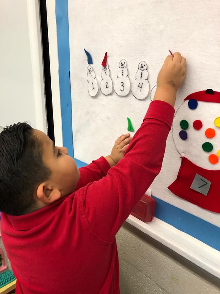 Child placing a felt piece on a wall display