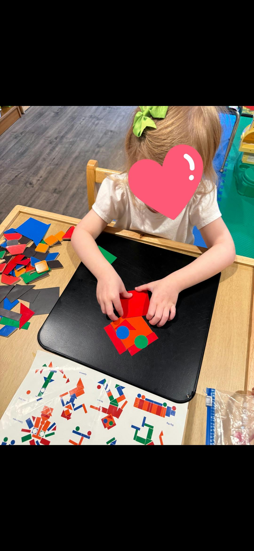 Child arranging colorful geometric magnets on a black magnetic board