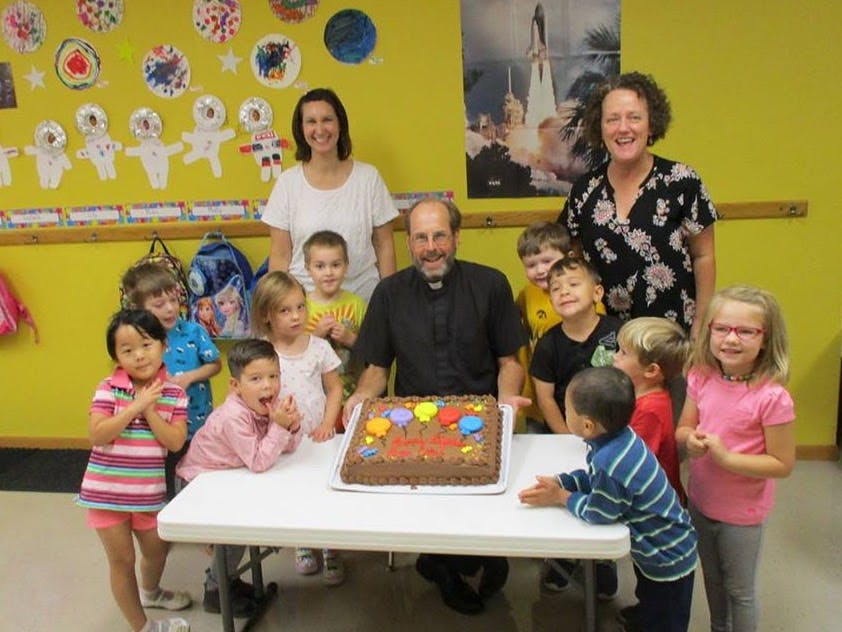 Adults and children gathered around a table with a birthday cake