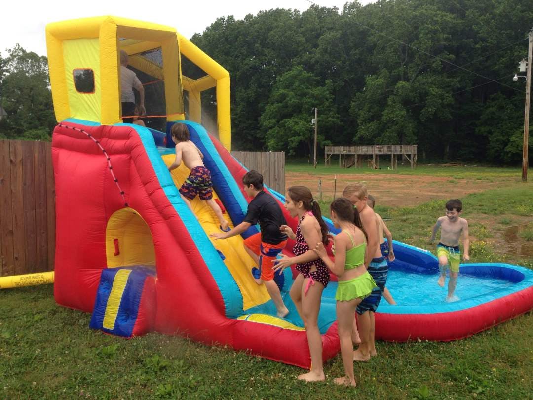 Children playing on an inflatable water slide with a small pool