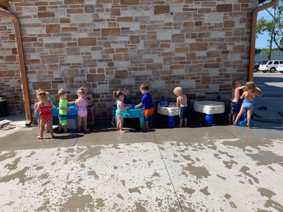 Children playing with water tables outdoors