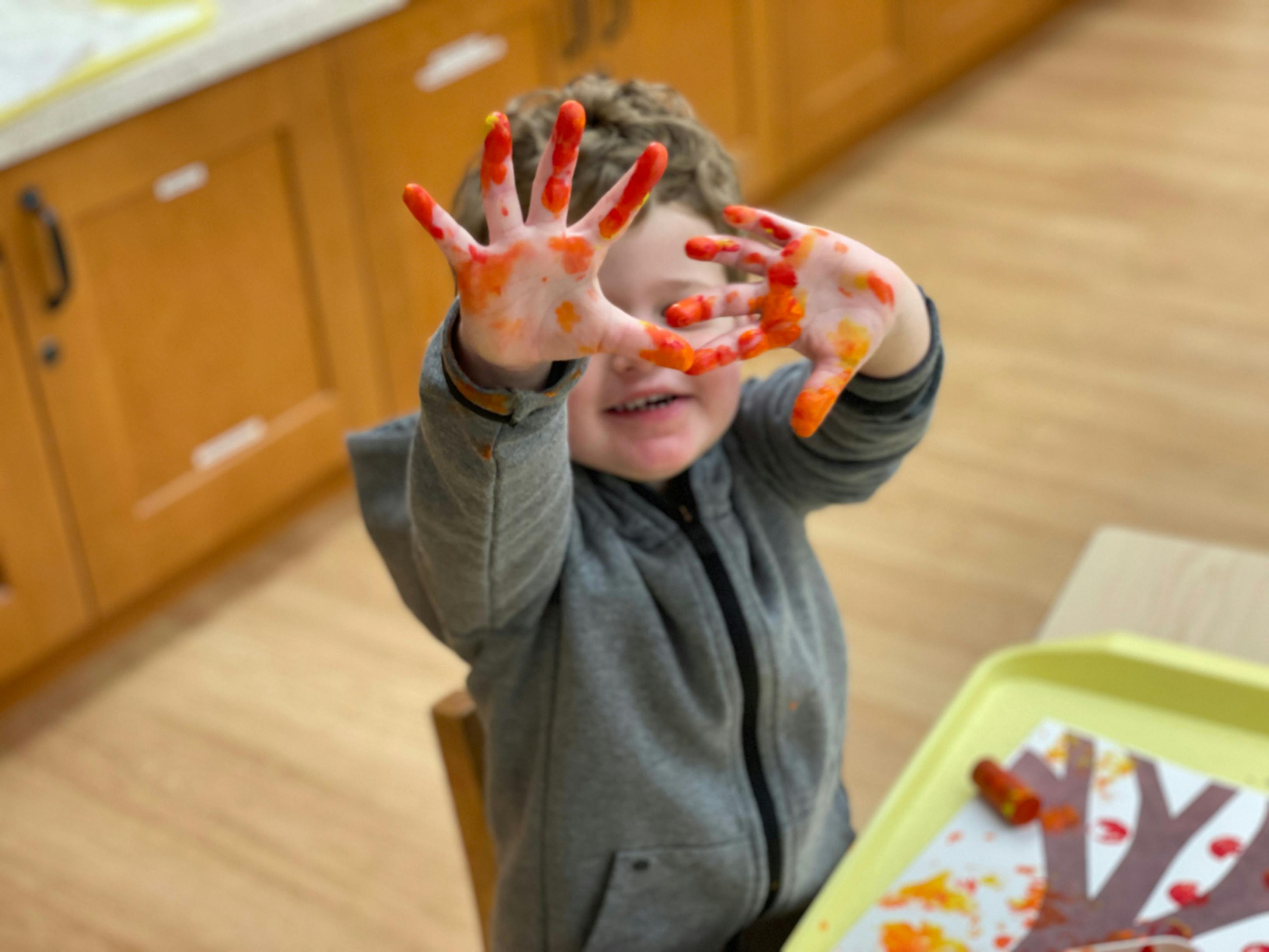Child with paint on hands holding them up