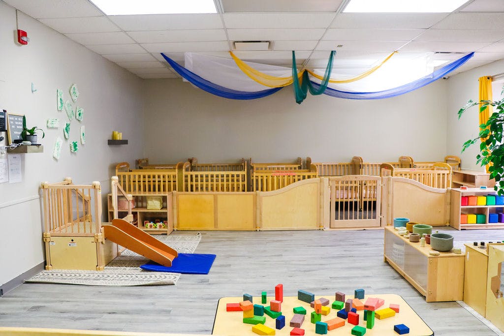 Nursery room with cribs, a small slide, and colorful building blocks