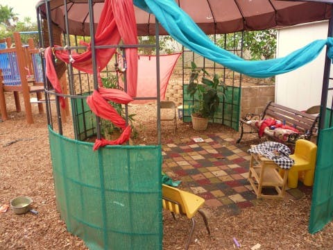 Outdoor gazebo with red and blue fabric draped over the frame