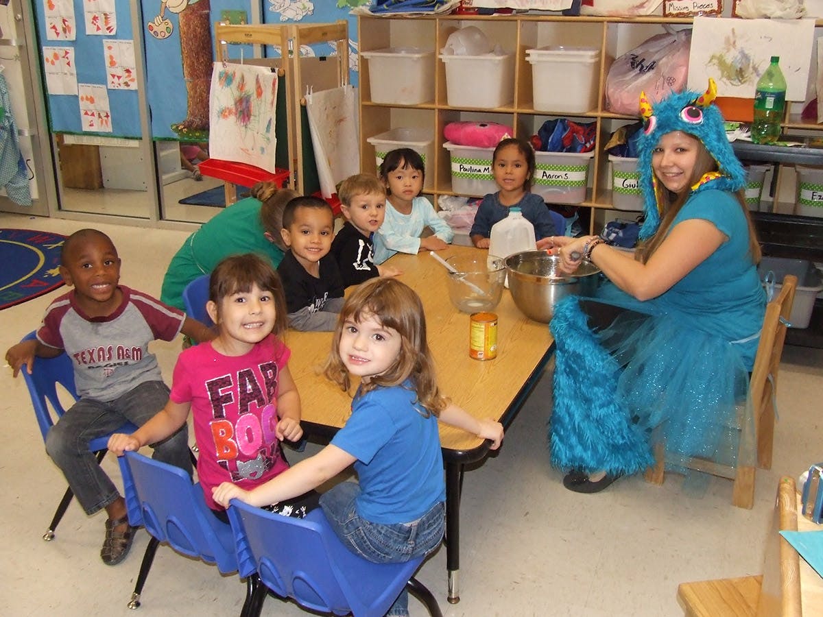Adult in monster costume with children at a table
