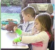 Two children sitting at a table doing an activity