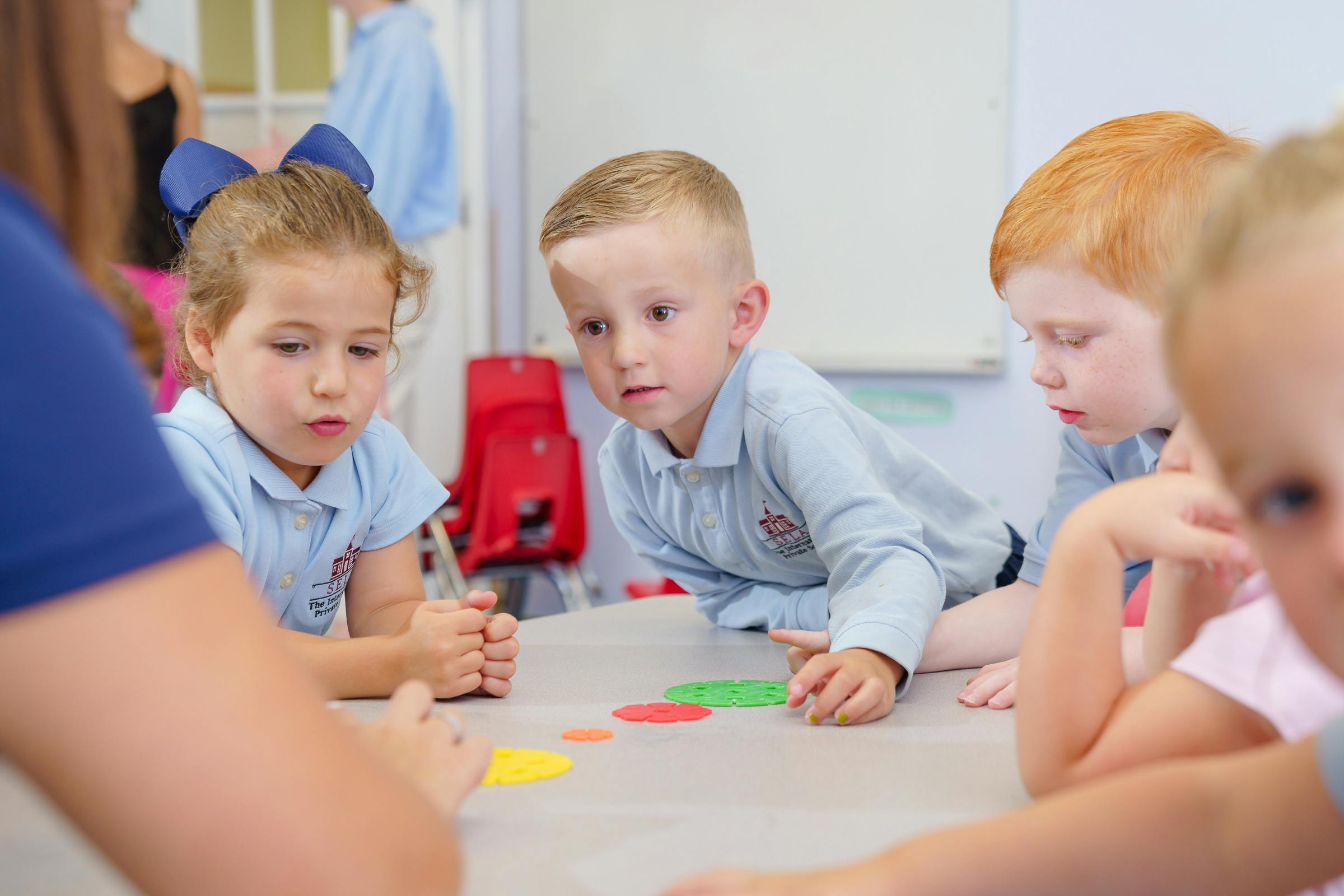 Children at a table looking at colorful shapes