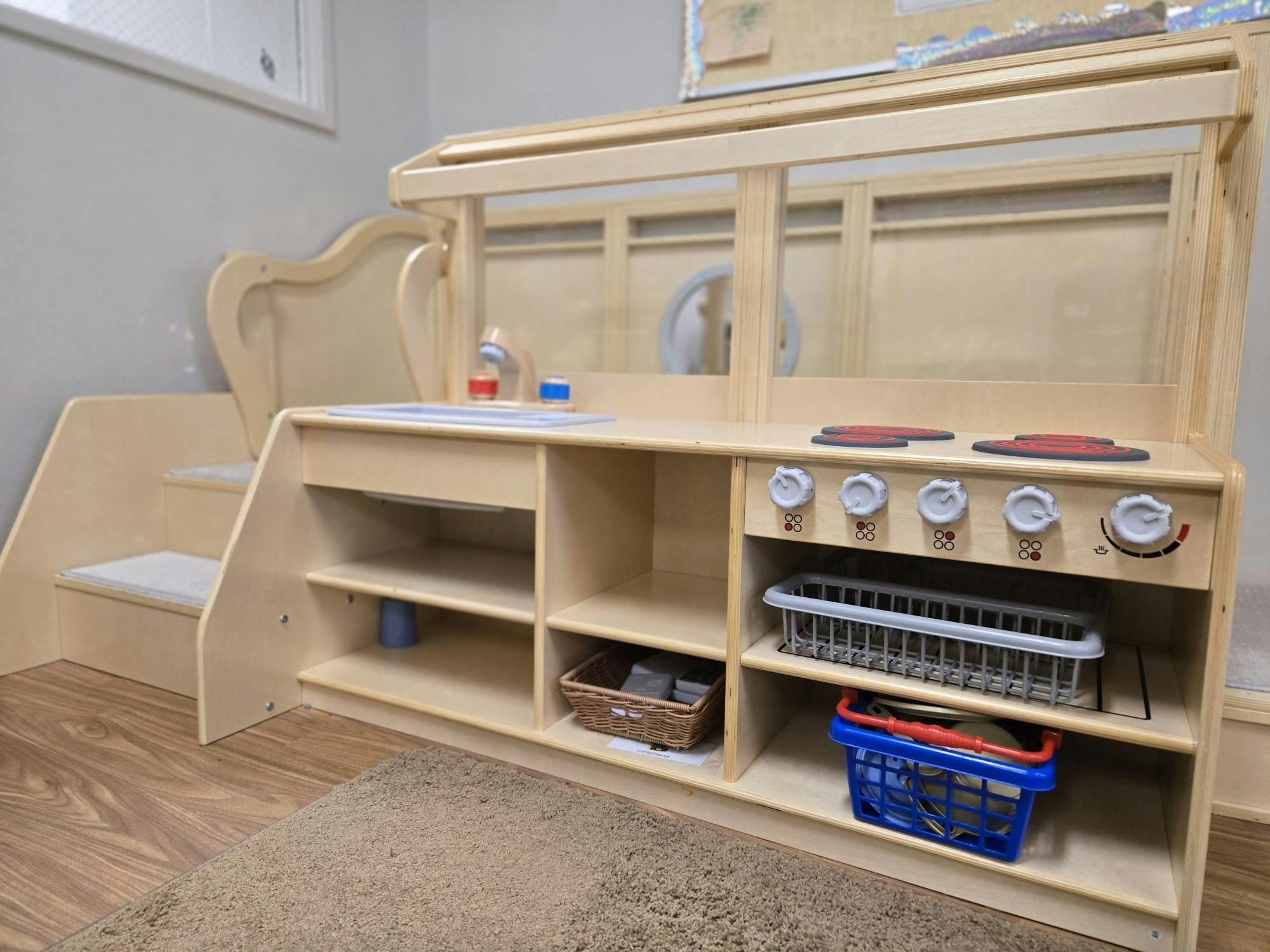 Wooden play kitchen with shelves, sink, and stove burners